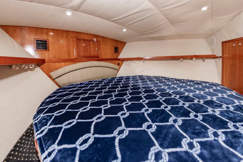 Slide: The Image of The cabin of the 2004 Albemarle 410 Express Fisherman features a large bed with a blue patterned cover. - 43