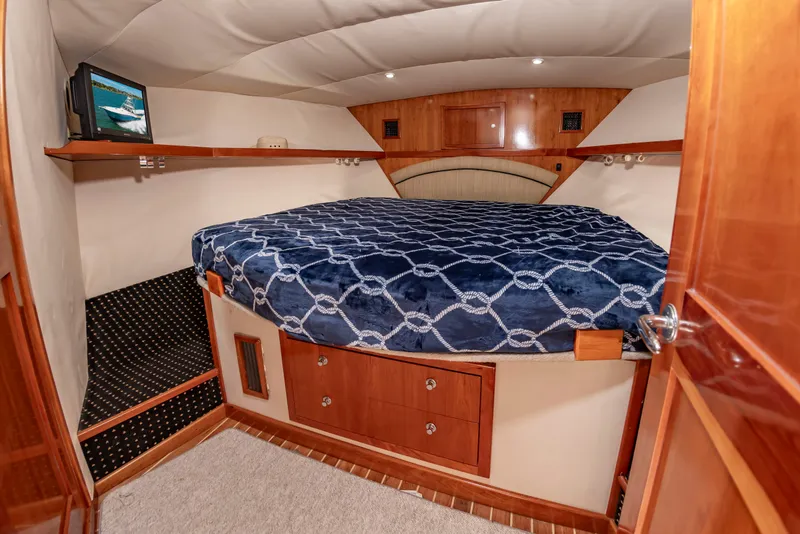 Slide: The Image of Cabin with a large bed, wooden cabinetry, and a small TV on a shelf. - 42