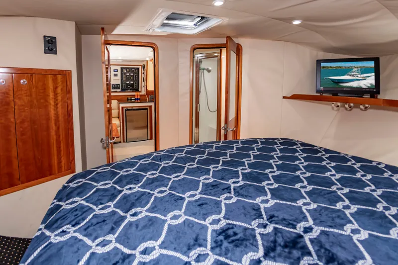 Slide: The Image of The cabin of a 2004 Albemarle 410 Express Fisherman with a bed, TV, and wooden furnishings. - 44