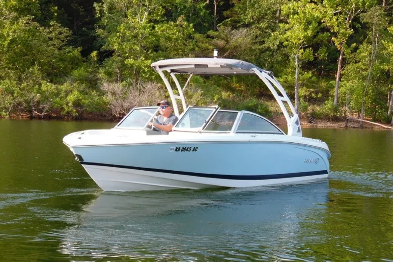 Slide: The Image of 2020 Cobalt 220S boat cruising on a serene lake with lush green trees. - 7