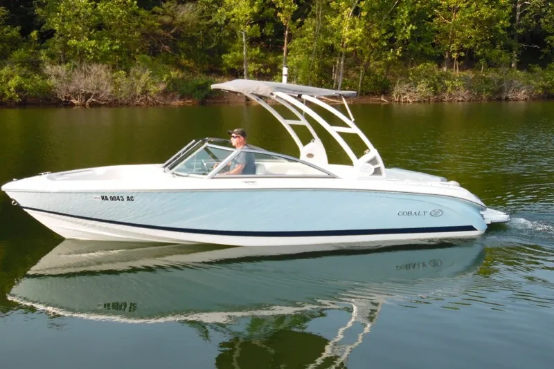 Slide: The Image of 2020 Cobalt 220S boat cruising on a serene lake with lush green trees in the background. - 6