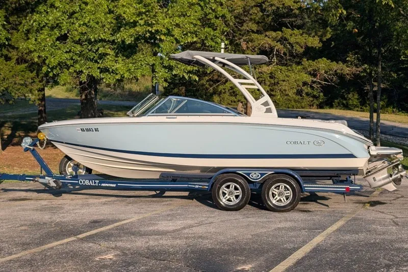 Slide: The Image of 2020 Cobalt 220S boat on trailer, parked outdoors with trees in background. - 1