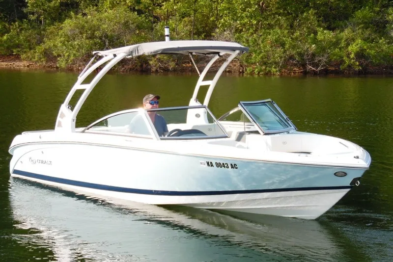 The Image of 2020 Cobalt 220S boat cruising on a serene lake with lush greenery. - 3