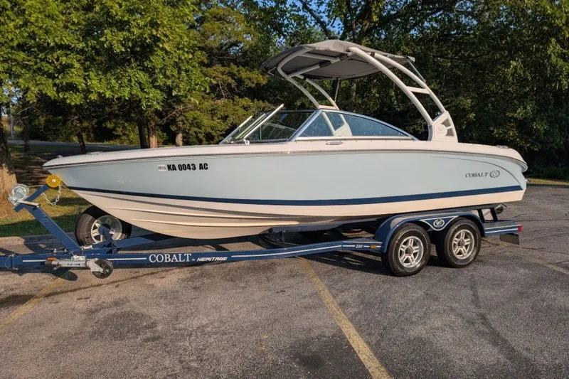Slide: The Image of 2020 Cobalt 220S boat on trailer, parked outdoors, surrounded by trees. - 0