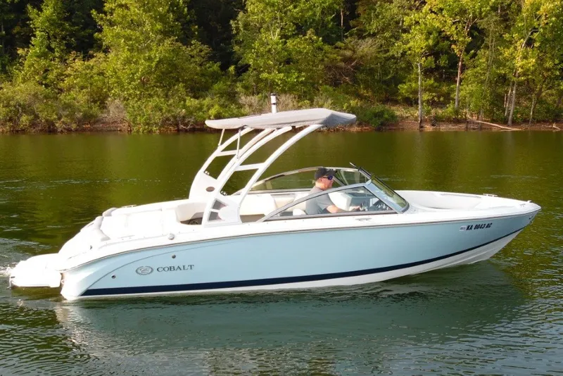 Slide: The Image of 2020 Cobalt 220S boat cruising on a serene lake with lush green trees in the background. - 4