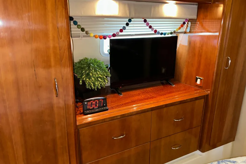Slide: The Image of Interior of 2003 Carver 466 Motor Yacht with TV, clock, and plant on wooden cabinet. - 46