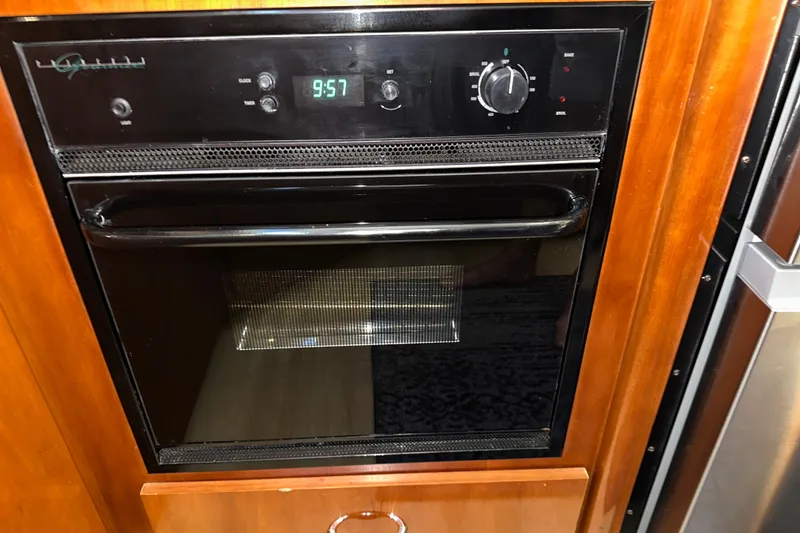 Slide: The Image of Built-in oven on 2003 Carver 466 Motor Yacht, featuring digital clock and control knobs. - 25