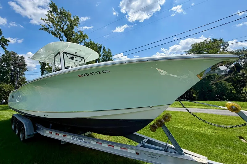 Slide: The Image of 2017 Sea Hunt Gamefish 30CB boat on trailer, parked on grass under blue sky. - 18