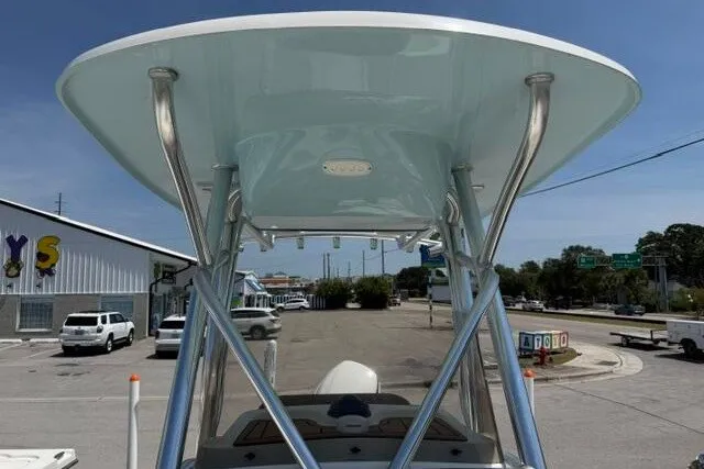 Slide: The Image of 2025 Pioneer 220 Bay Sport boat with T-top, parked in a sunny urban area. - 18