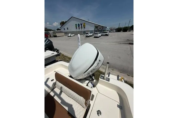 Slide: The Image of 2025 Pioneer 220 Bay Sport boat with motor, parked near a toy store under a clear sky. - 27