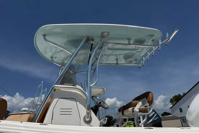 Slide: The Image of 2025 Pioneer 220 Bay Sport boat with T-top and seating, under clear blue sky. - 9