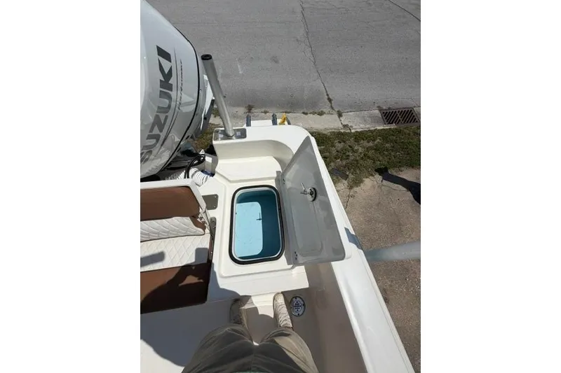 Slide: The Image of 2025 Pioneer 220 Bay Sport boat with open storage compartment and Suzuki engine. - 26