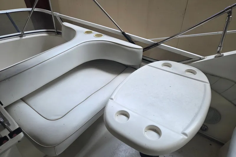 Slide: The Image of 1997 Sea Ray 440 Express Bridge interior with white seating and table featuring cup holders. - 14
