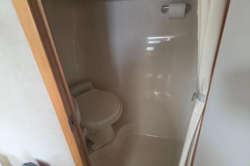Slide: The Image of Bathroom interior of 1997 Sea Ray 440 Express Bridge yacht, featuring toilet and shower. - 25