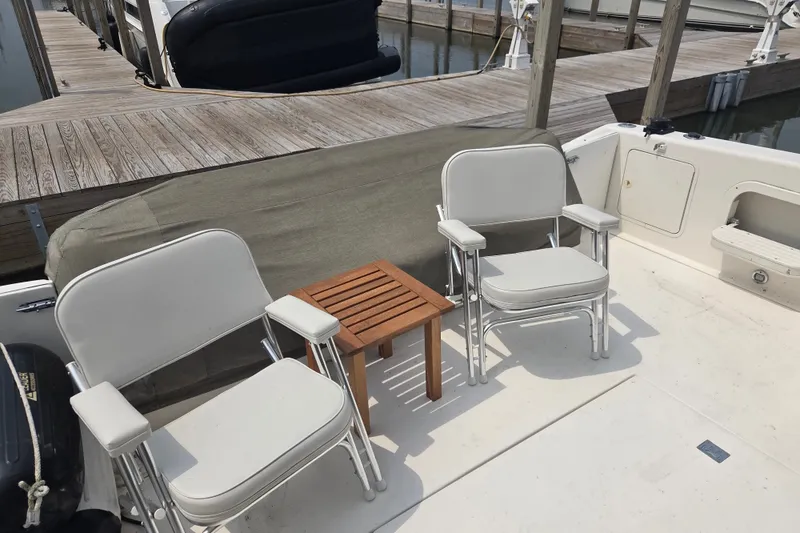Slide: The Image of Deck seating on a 1997 Sea Ray 440 Express Bridge yacht, featuring two chairs and a table. - 5