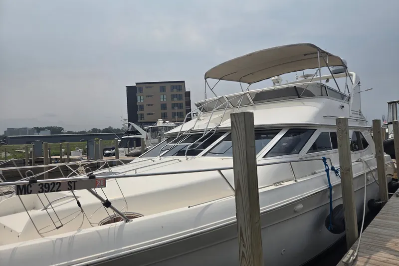 Slide: The Image of 1997 Sea Ray 440 Express Bridge yacht docked at marina, featuring sleek design and spacious deck. - 1