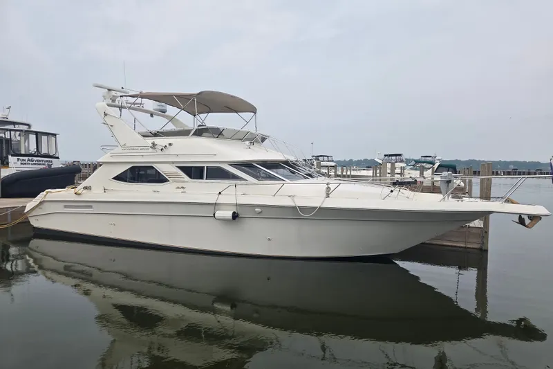 The Image of 1997 Sea Ray 440 Express Bridge yacht docked at marina, side view. - 0