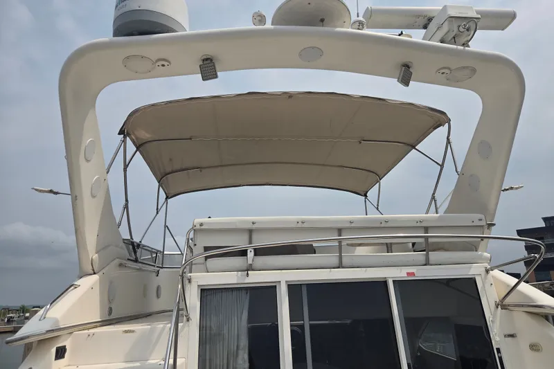 Slide: The Image of 1997 Sea Ray 440 Express Bridge yacht with canopy, docked under a cloudy sky. - 3