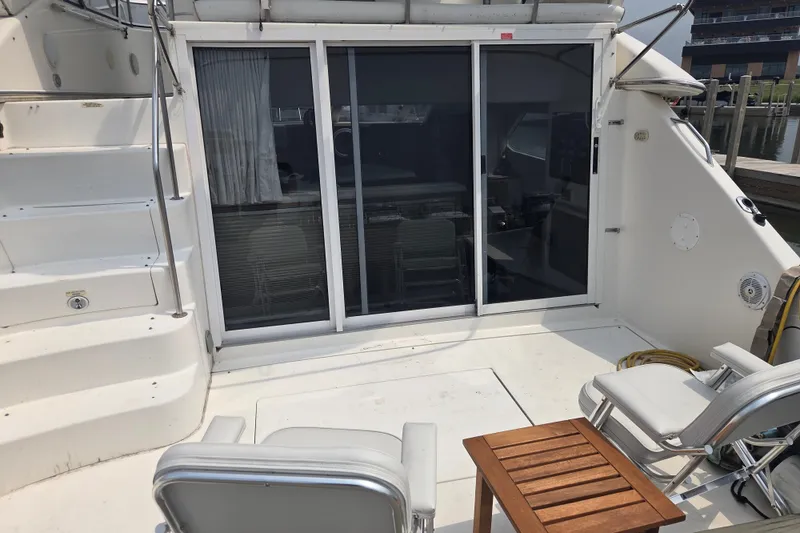 Slide: The Image of 1997 Sea Ray 440 Express Bridge yacht deck with seating and sliding glass doors. - 2