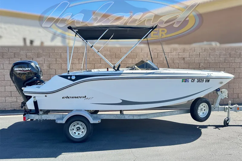 The Image of 2023 Bayliner Element M17 boat on trailer with Mercury engine, parked outdoors. - 0