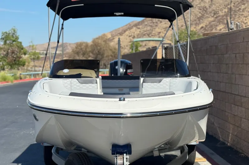 Slide: The Image of 2023 Bayliner Element M17 boat with canopy, parked on a sunny day. - 2