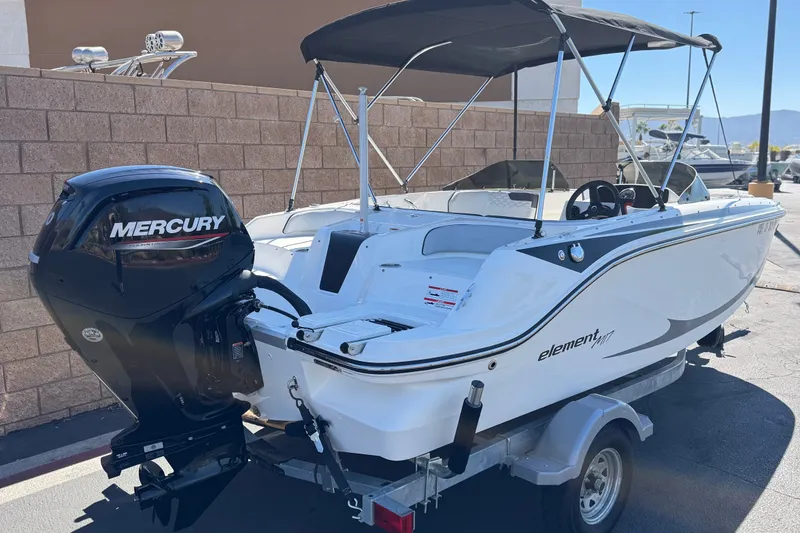 Slide: The Image of 2023 Bayliner Element M17 boat with Mercury engine on trailer, parked outdoors. - 5