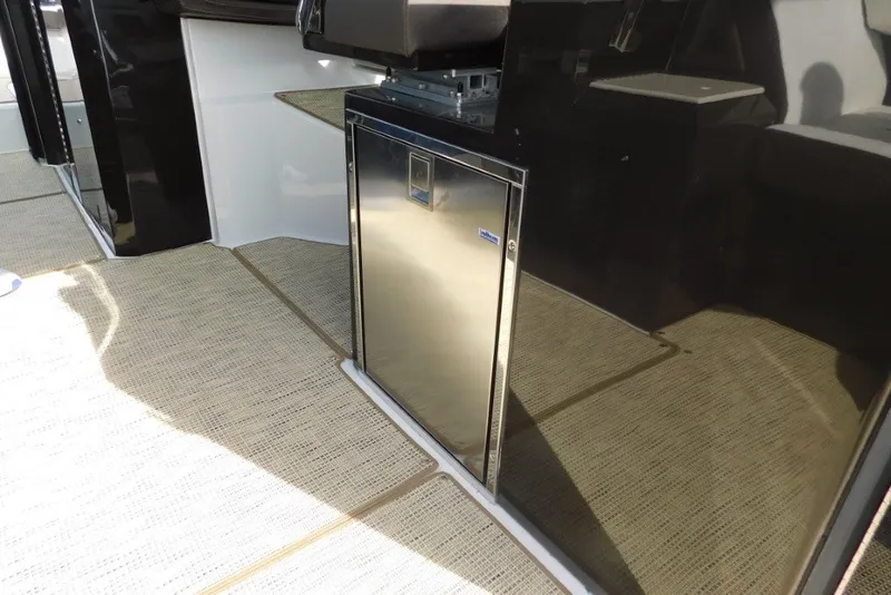 Slide: The Image of 2019 Cobalt A36BR boat interior with stainless steel mini fridge and beige flooring. - 13