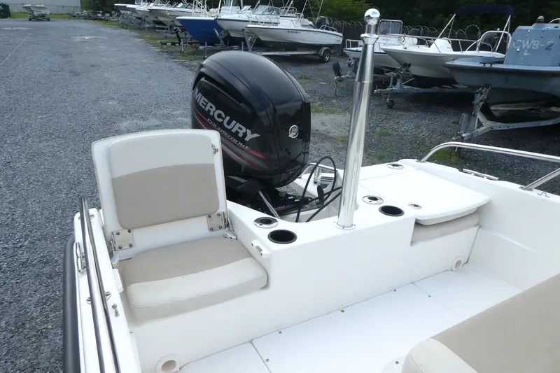 Slide: The Image of 2017 Boston Whaler 170 Dauntless boat with Mercury engine, parked in a gravel lot. - 5