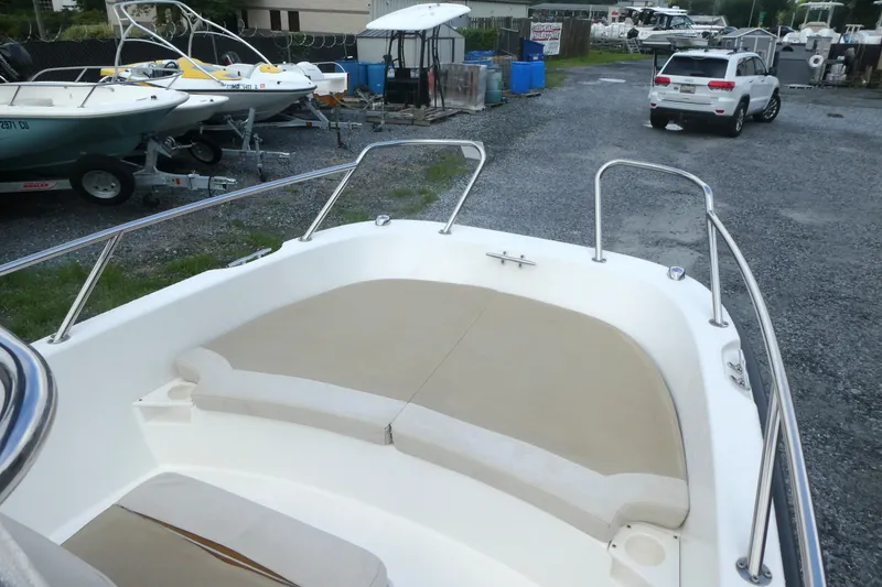 Slide: The Image of 2017 Boston Whaler 170 Dauntless boat with cushioned seating, parked in a gravel lot. - 9