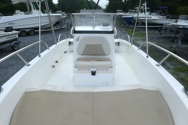 Slide: The Image of 2017 Boston Whaler 170 Dauntless boat interior with seating and console, parked among other boats. - 10