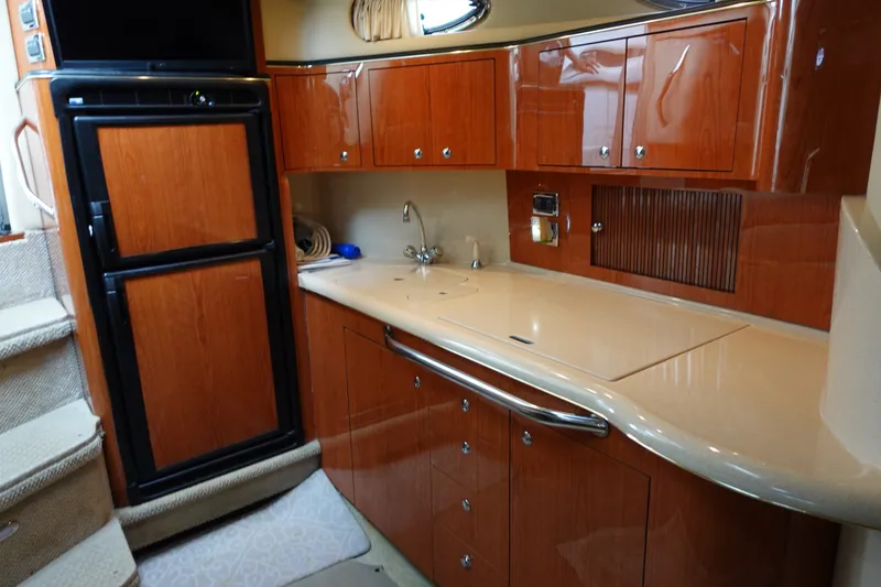 Slide: The Image of Interior of 2001 Sea Ray 410 Express Cruiser with wooden cabinetry and compact kitchen area. - 15