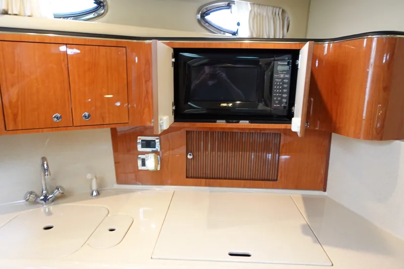 Slide: The Image of 2001 Sea Ray 410 Express Cruiser kitchen with microwave, sink, and wooden cabinetry. - 16