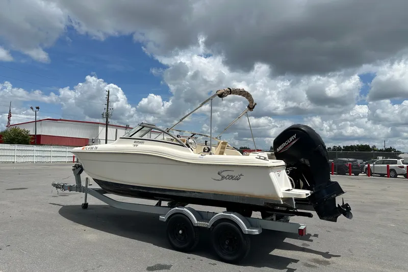 Slide: The Image of 2023 Scout 210 Dorado boat on trailer under cloudy sky. - 2