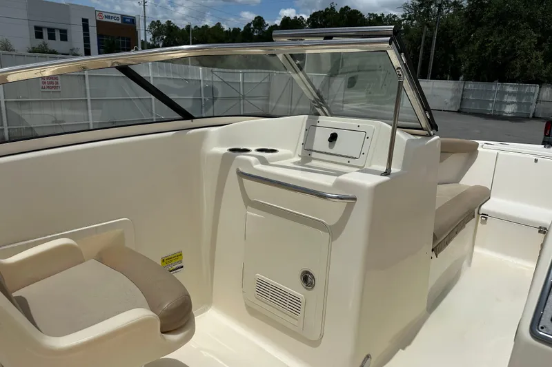 Slide: The Image of 2023 Scout 210 Dorado boat interior with seating and console, parked outdoors. - 11