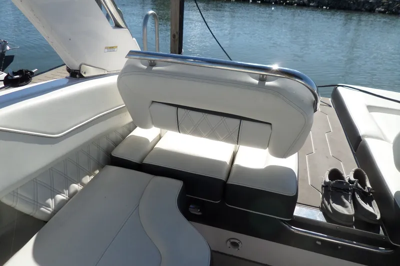 Slide: The Image of 2020 Regal LS6 boat interior with white seating and shoes on deck by the water. - 40