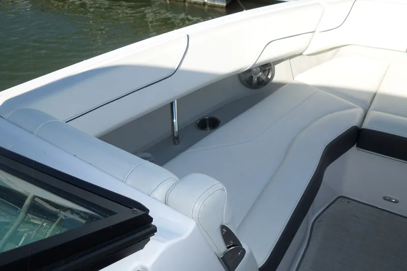 Slide: The Image of 2020 Regal LS6 boat interior with white seating and cup holder by the water. - 16