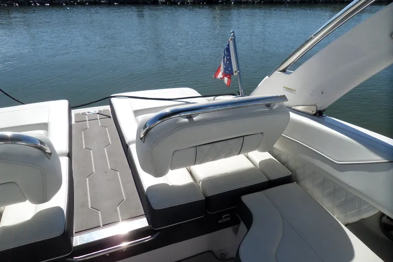 Slide: The Image of 2020 Regal LS6 boat interior with white seating and American flag on calm water. - 39