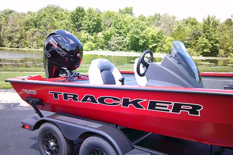The Image of Red 2027 Tracker Pro Team 195 boat parked by a scenic lake. - 0