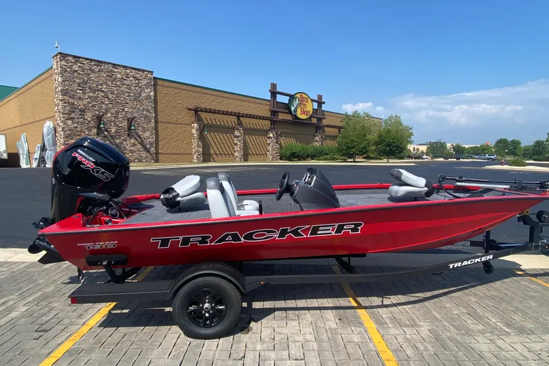 The Image of 2027 Tracker Pro Team 190 boat in a parking lot, near a Bass Pro Shops store. - 0