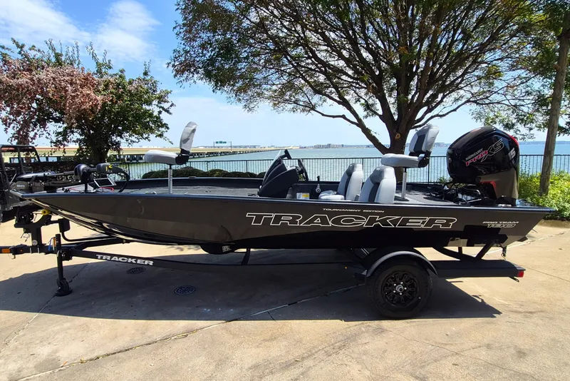 The Image of 2027 Tracker Pro Team 190 boat on trailer by waterfront, under a tree. - 0