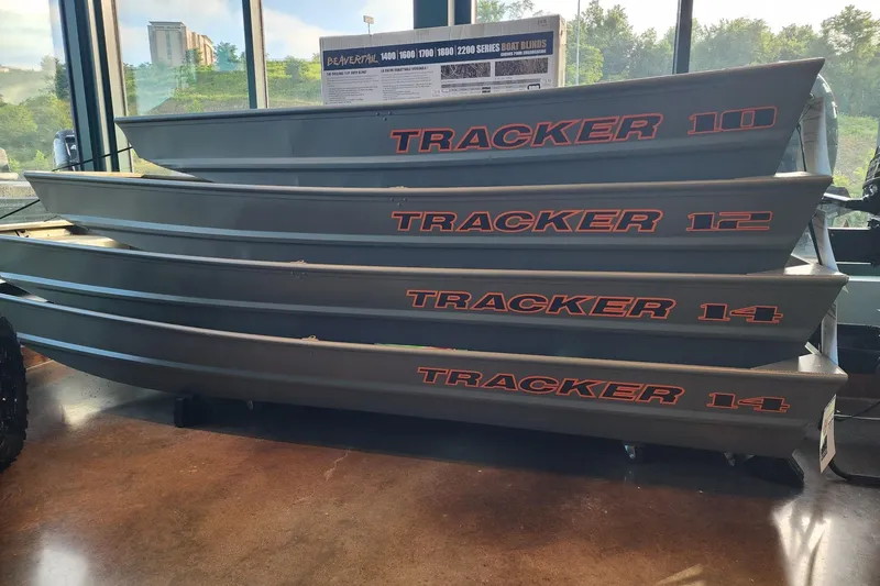 The Image of Stacked Tracker Jon boats, including 2027 Grizzly 12 model, displayed indoors. - 0