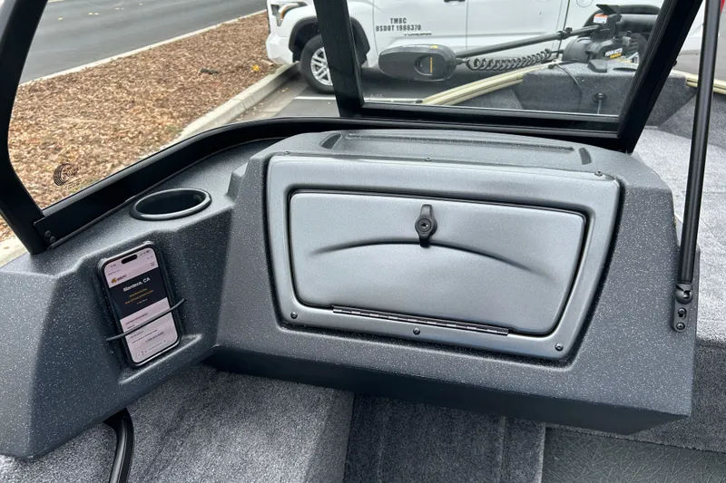 Slide: The Image of Interior of 2027 Tracker Pro Guide V-16 WT boat with storage compartment and phone holder. - 26