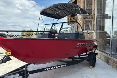 The Image of 2027 Tracker Pro Guide V-16 WT boat with canopy on trailer, parked outdoors. - 0