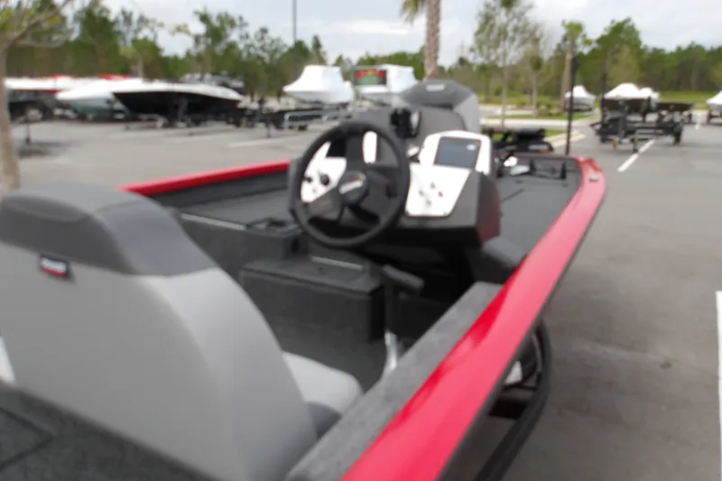 Slide: The Image of 2027 Tracker Pro Team 190 boat with red trim in a parking lot. - 14