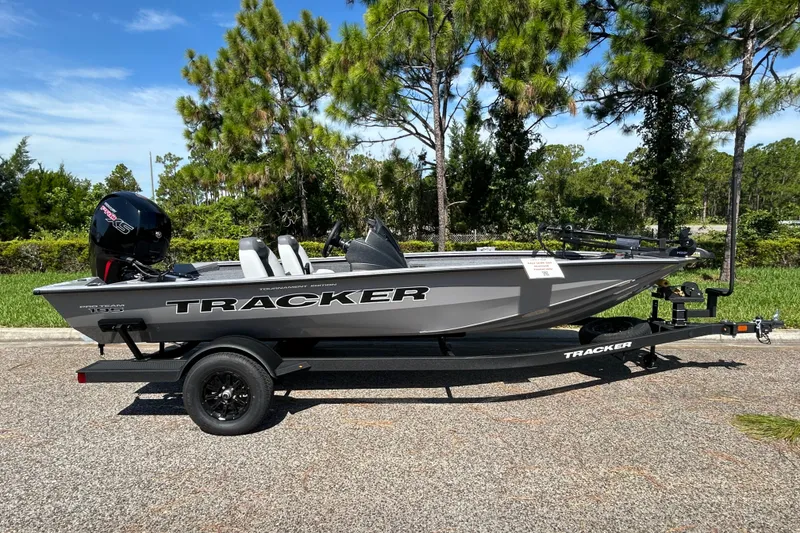 The Image of 2027 Tracker Pro Team 195 boat on trailer, parked outdoors with trees in the background. - 0