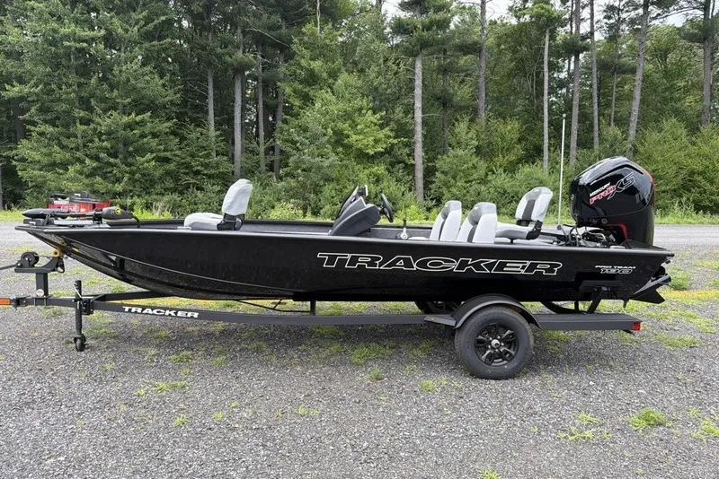 The Image of 2027 Tracker Pro Team 190 boat on trailer, parked outdoors with forest background. - 0