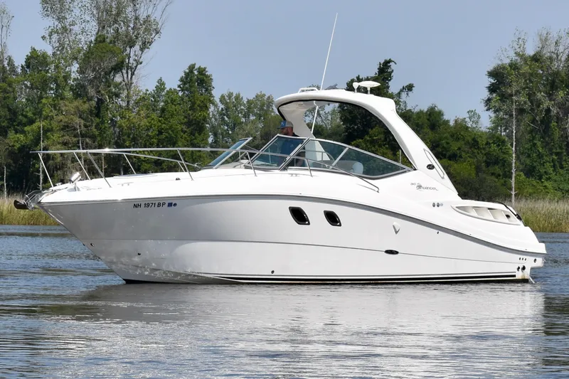 Slide: The Image of 2008 Sea Ray Sundancer 310 cruising on a calm lake with lush greenery. - 4