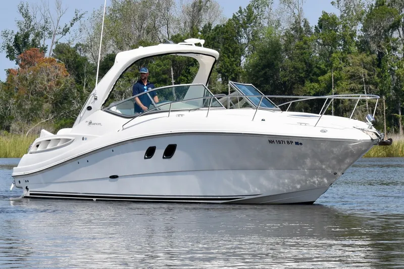 The Image of 2008 Sea Ray Sundancer 310 cruising on a calm lake with lush greenery in the background. - 1