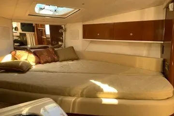 Slide: The Image of 2008 Sea Ray Sundancer 310 cabin interior with bed, pillows, and wooden cabinets. - 10