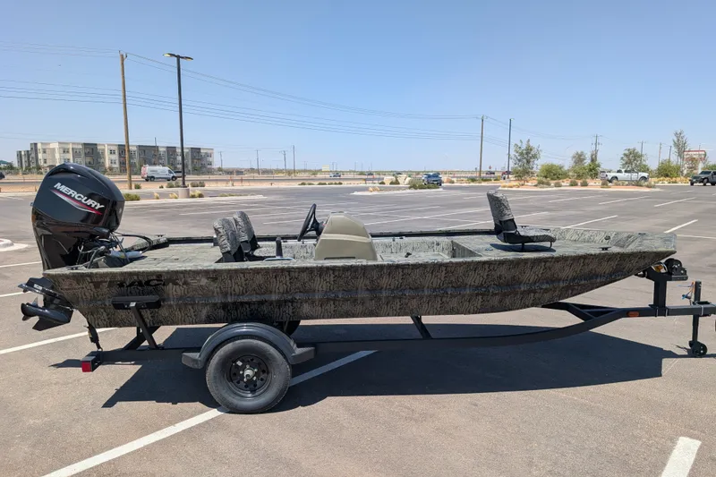 The Image of 2027 Tracker Grizzly 1754 SC boat on trailer in parking lot, featuring Mercury outboard motor. - 0